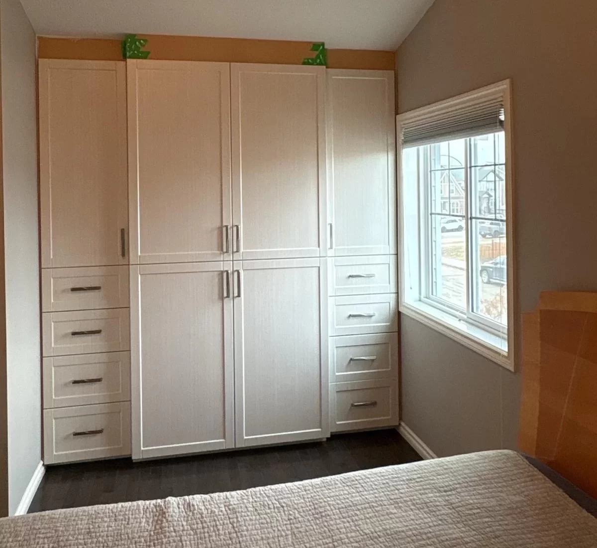 Completed custom master bedroom closet organizer installed beneath a vaulted ceiling with thermofoil shaker doors, soft-close drawers, and floor-to-ceiling cabinetry.